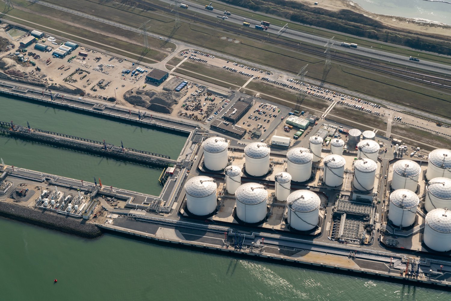 aerial view of a port storage terminal with tanks and jetties, an energy infrastructure project